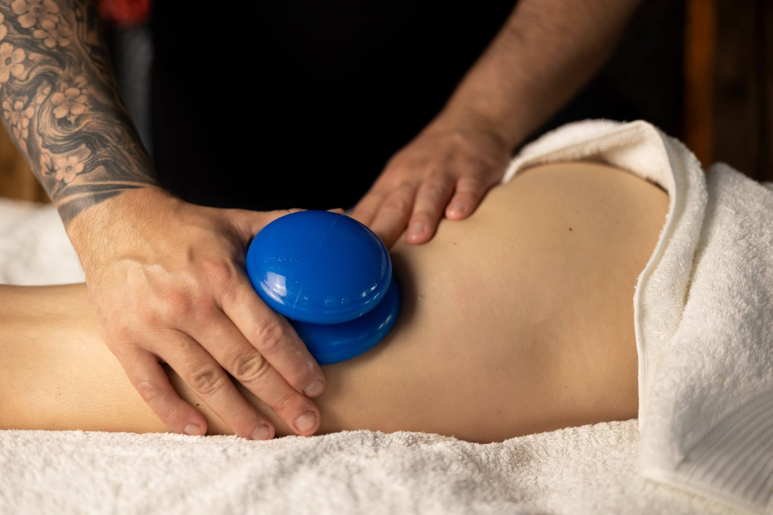 Terapeuta wykonujący masaż antycellulitowy bańka chińską na udach klientki w profesjonalnym gabinecie masażu, stosując techniki poprawiające wygląd skóry