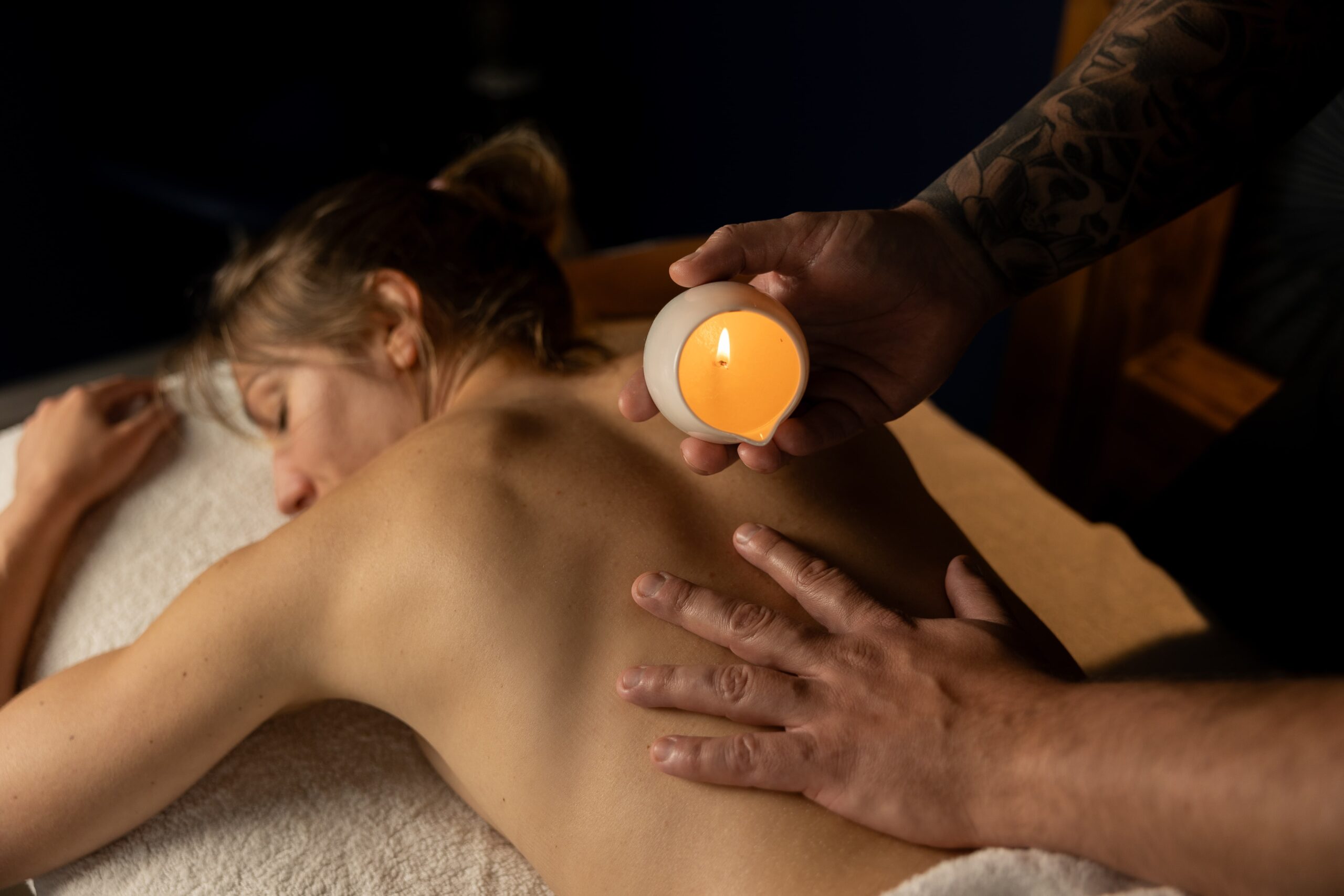 Specjalista wykonujący masaż ciepłą aromatyczną świecą na plecach pacjenta, tworząc relaksującą atmosferę i poprawiając samopoczucie