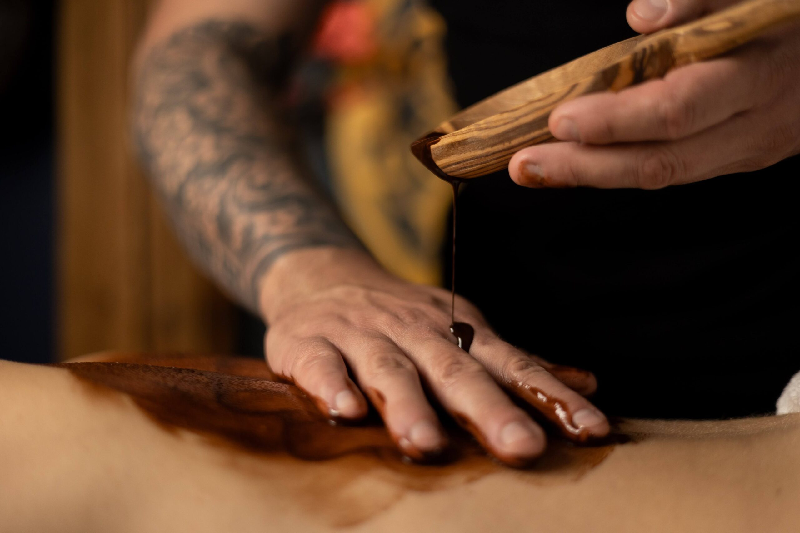 Terapeuta wykonujący masaż ciepłą czekoladą na plecach pacjenta