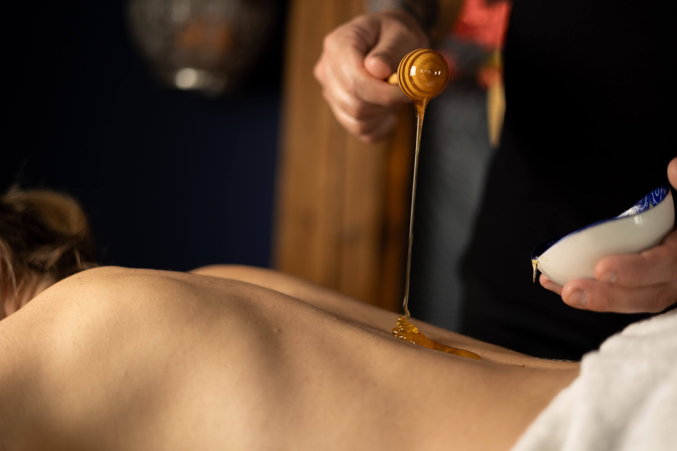 Terapeuta wykonujący masaż miodem na plecach pacjentki