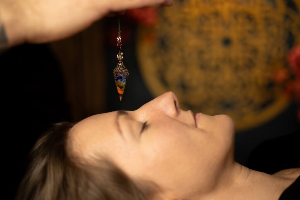 Zdjęcie przedstawia masażystę wykonującego holistyczny masaż z wahadłem