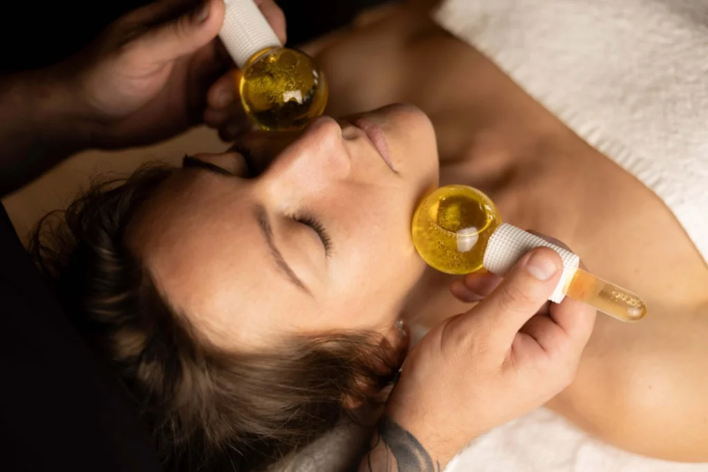 Masaż twarzy w stylu SPA wykonywany na kulach lodowych przez instruktora Akademii Oriental SPA – modelka leży z zamkniętymi oczami i relaksuje się podczas zabiegu